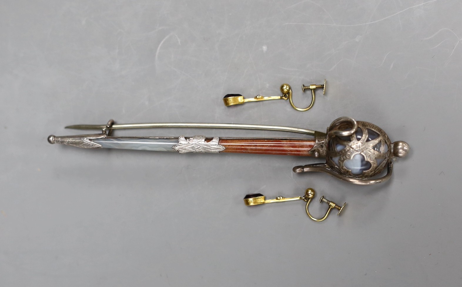 A pair of 9ct, amethyst and seed pearl set drop earrings, 20mm, gross weight 1.4 grams and a George V silver and Scottish hardstone mounted sword brooch, 11.8cm.